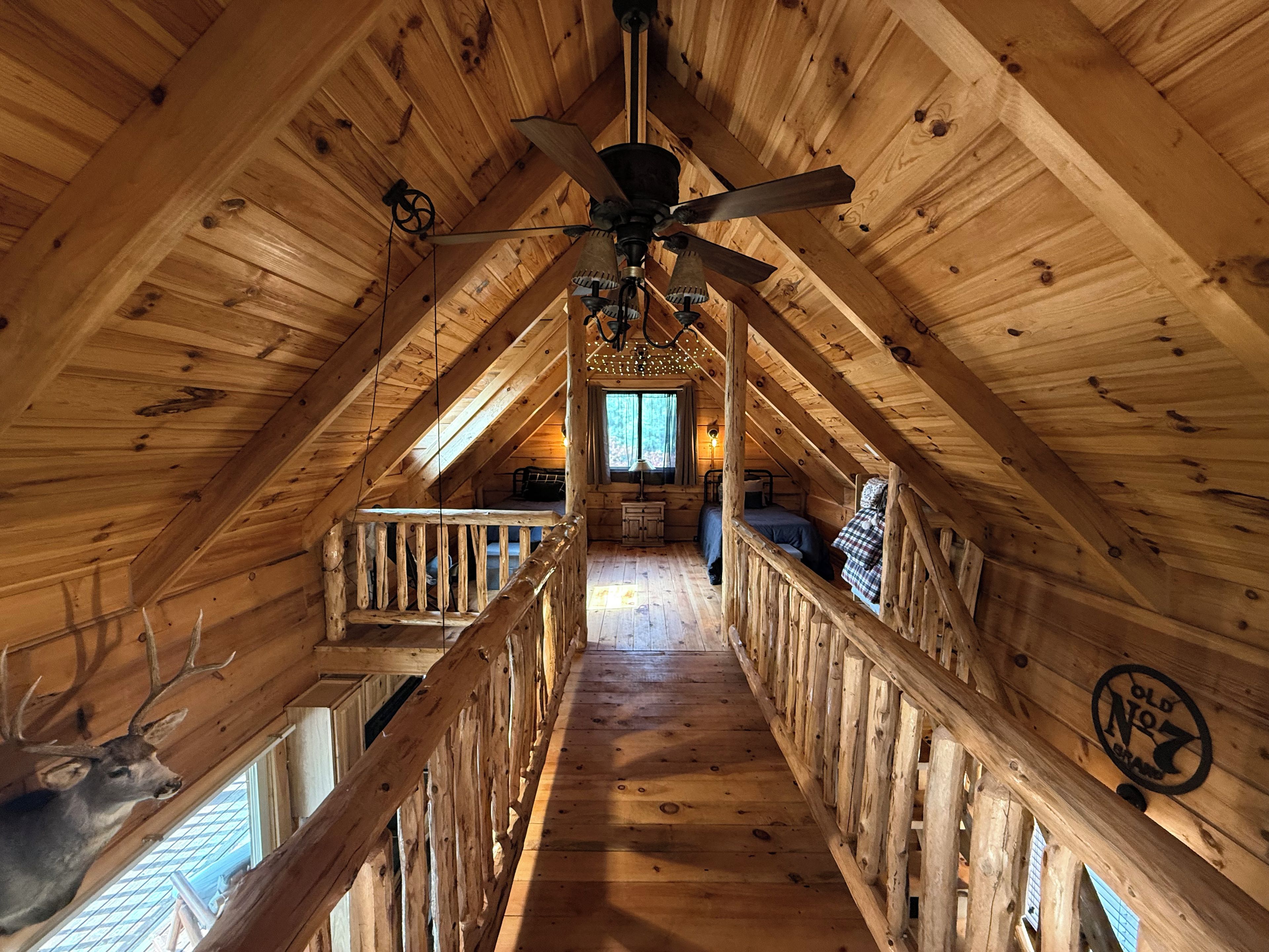 An attic bedroom with a wooden ceiling, a ceiling fan, a bed, and a window.