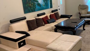 A living room with a sectional sofa, a coffee table, and a painting on the wall.