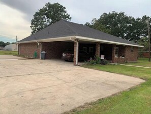Situated on a well-manicured lawn, this charming property features a covered front porch and a single-story brick building with a gabled roof.