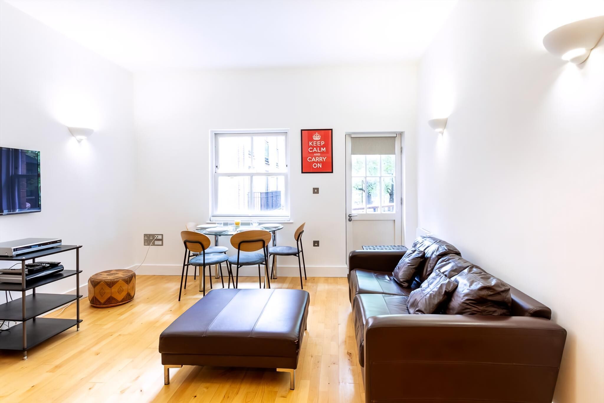 A modern living room with a sofa, ottoman, and dining area with chairs and a table.