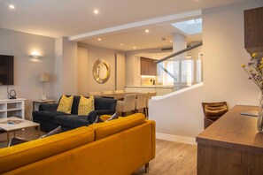 Un salon moderne comprenant un canapé, un coin repas et un escalier menant à un niveau supérieur.