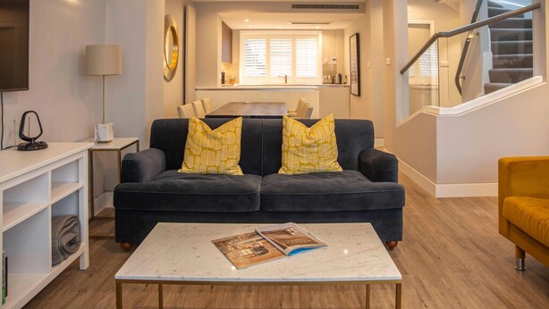 Ein Wohnzimmer mit einem dunklen Sofa, einem weißen Couchtisch und einem gelben Sessel.