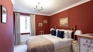 Quarto com uma cama grande, um candelabro, um penteado e uma janela com cortinas.