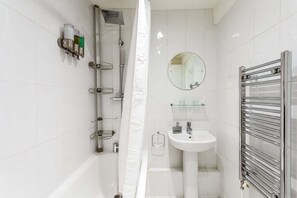 Ein modernes Badezimmer mit Dusche, Waschbecken, Spiegel und Handtuchhalter.
