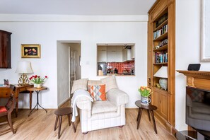 Ein Wohnzimmer mit einer Couch, einem Holzschrank, einem Fernseher und einem Essbereich mit Tisch und Stühlen.
