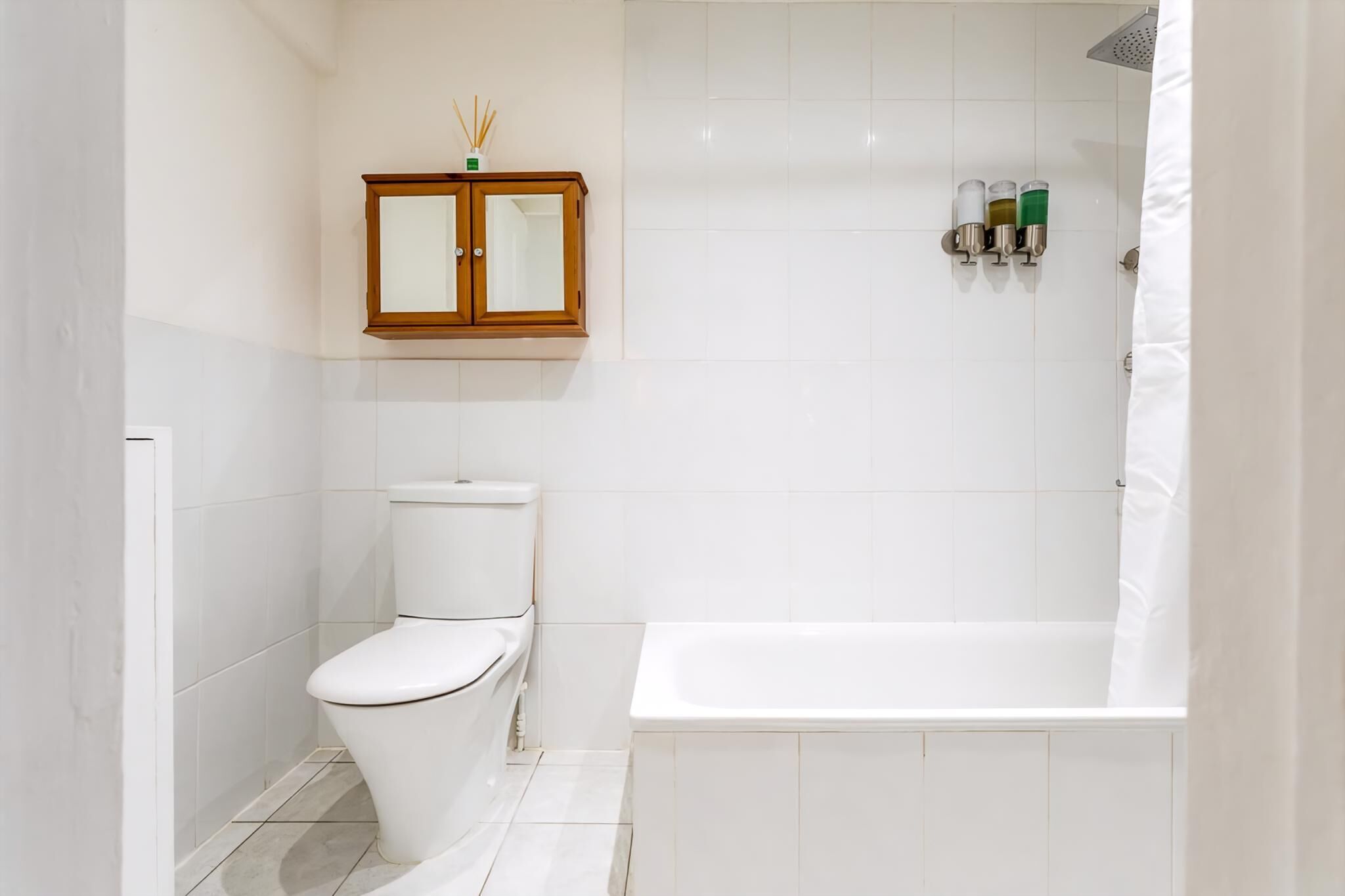 A bathroom with a toilet, a cabinet, and a bathtub.