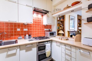 Eine moderne Küche mit weißen Schränken, einer roten Fliesenrückwand, einem Gasherd, einer Mikrowelle und einem Toaster.