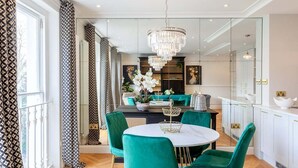 A modern dining area with a round table, teal chairs, and a chandelier.