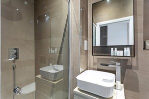 A modern bathroom with a glass-enclosed shower, a white sink, and a large mirror above the sink. - Stunning Earls Court Flat (London)