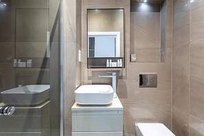 A modern bathroom with a glass-enclosed shower, a white sink with a rectangular basin, and a mirror above the sink. - Stunning Earls Court Flat (London)