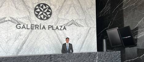 Ein Mann steht vor einem Schild für Galeria Plaza, mit einer Marmorwand und einem schwarzen Marmorboden.
