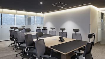 Un salón de conferencias con una gran mesa, varias sillas y un teléfono sobre la mesa.