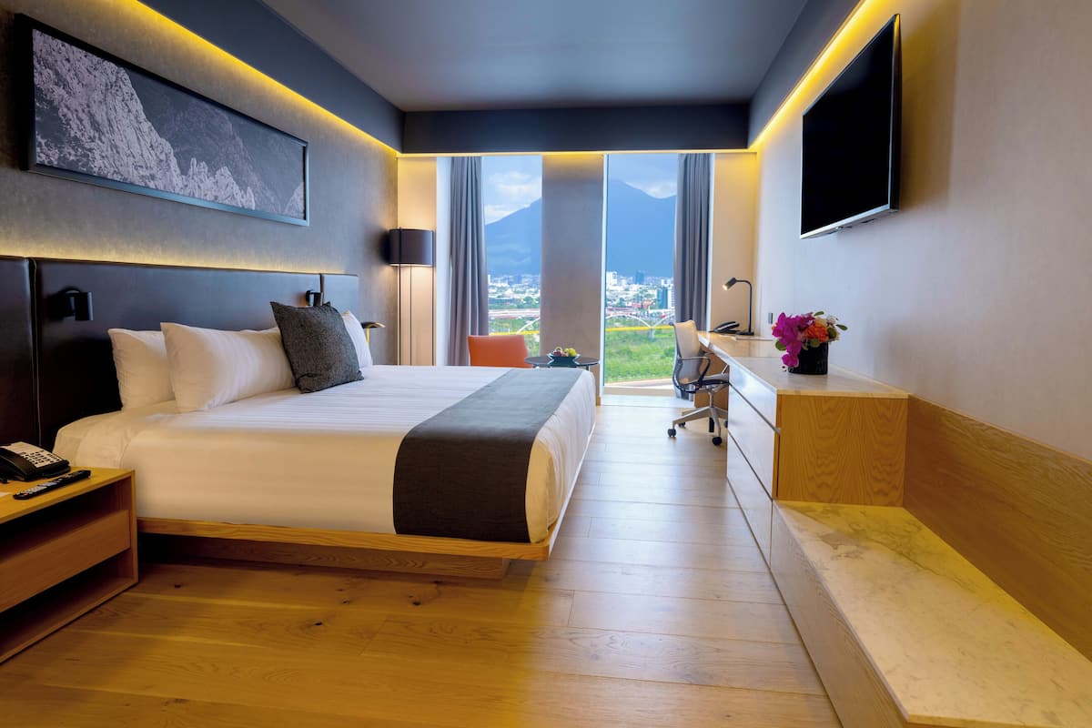 Une chambre d’hôtel moderne avec un grand lit, un bureau et une vue sur le paysage urbain.