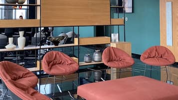 Een modern interieur met een glazen dak, houten en metalen planken, en rode zachte zitplaatsen.