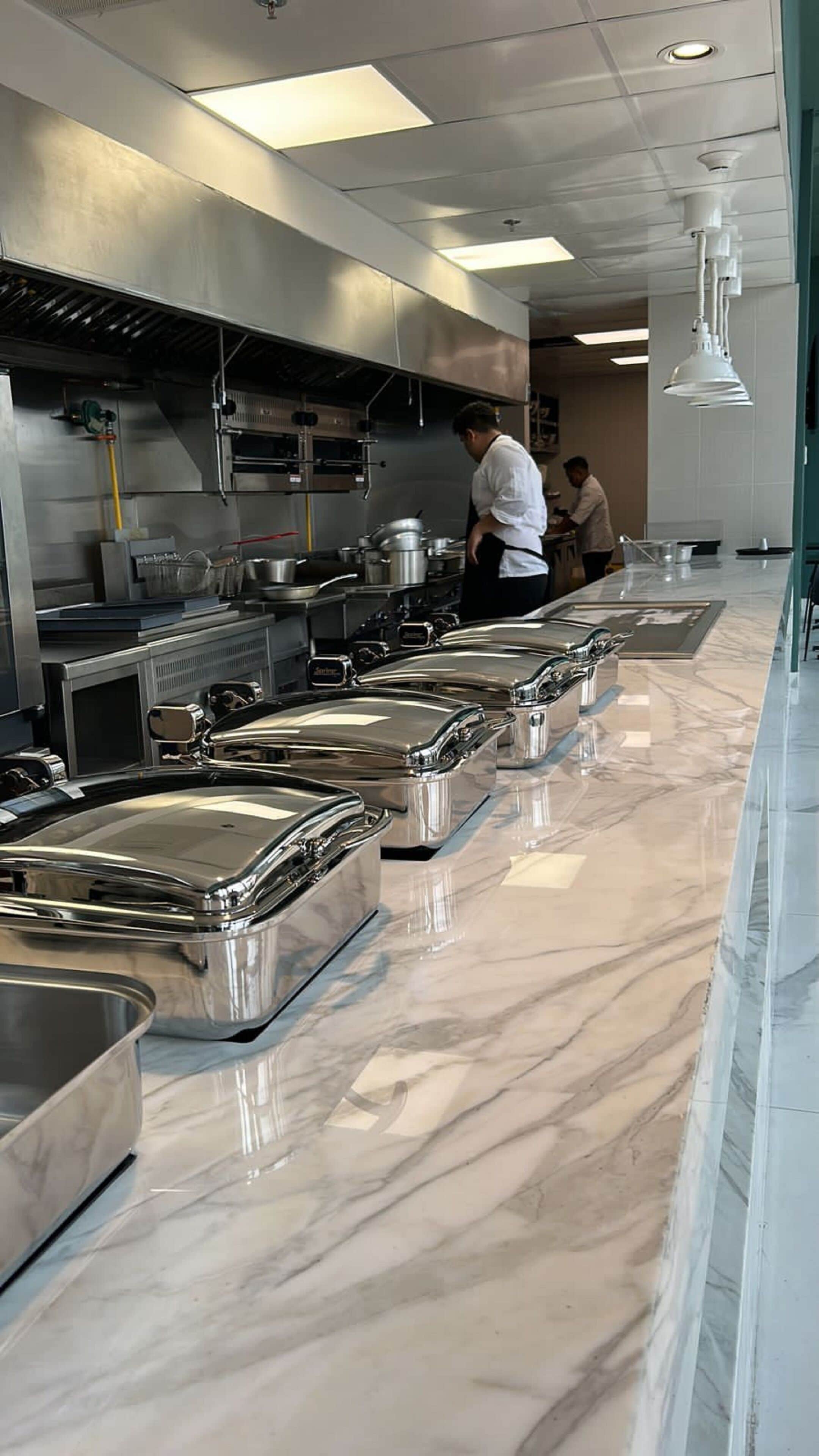 Een professionele keuken met roestvrijstalen apparatuur en marmeren aanrechtbladen.