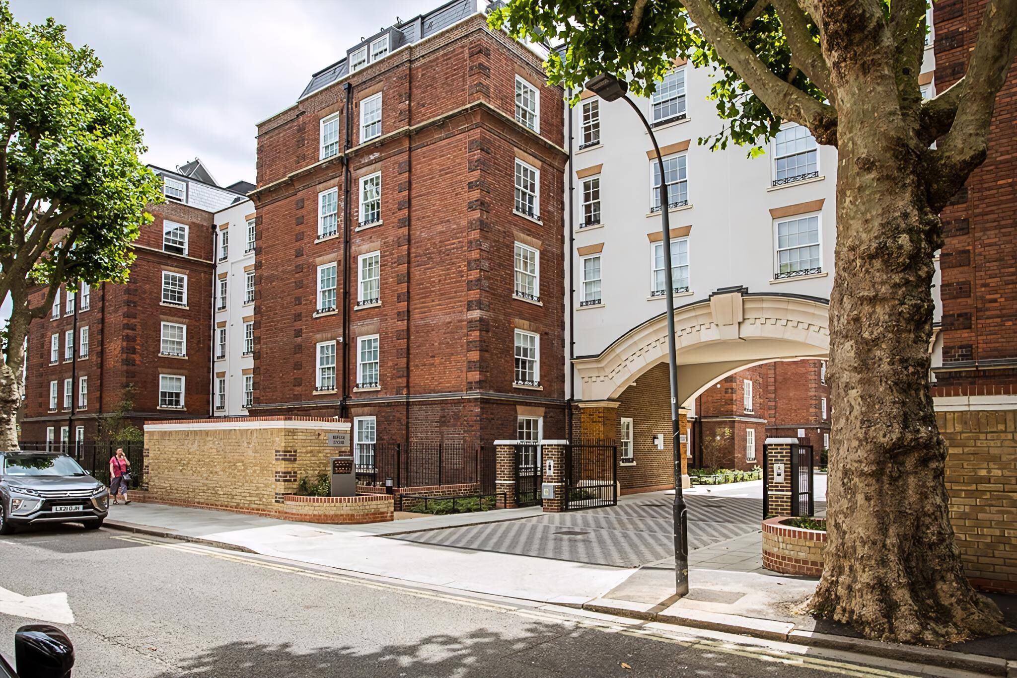 A multi-story building with brick facades, large windows, and a gated entrance.
