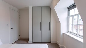 Une chambre à coucher avec un lit, une armoire, une fenêtre et une porte.