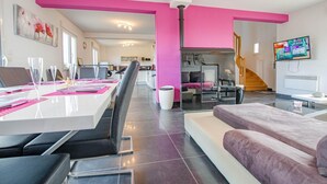 Un salon moderne comprenant un coin repas, un canapé, un téléviseur et un escalier.