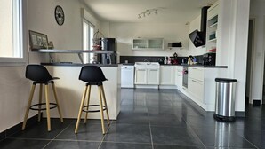 Une cuisine moderne équipée de deux tabourets de bar, d’un four à micro-ondes, d’un évier et d’une poubelle.