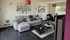 Un salon moderne avec un canapé gris, une table basse noire et des lampes suspendues rouges.