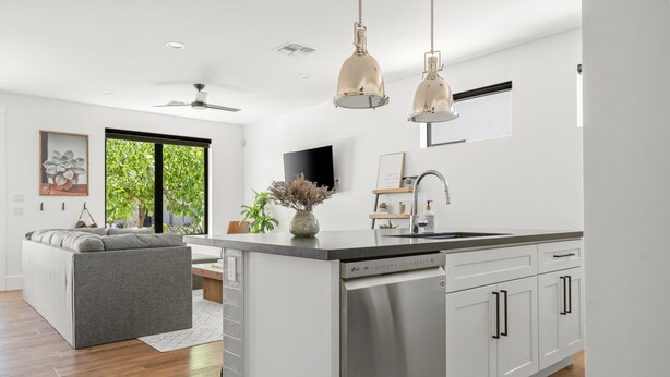 Una cocina moderna con una isla central, armarios blancos y un lavavajillas integrado.