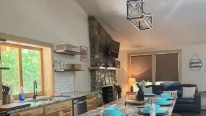 Une cuisine spacieuse dotée d’un grand îlot central, de meubles en bois et d’un mur d’accent en pierre.