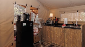 A compact kitchen with a refrigerator, coffee maker, fan, toaster, and wooden cabinets. - BEARADISE “Glamping Paradise” (Vesuvius)
