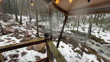 A wooden deck with a view of a snowy forest.