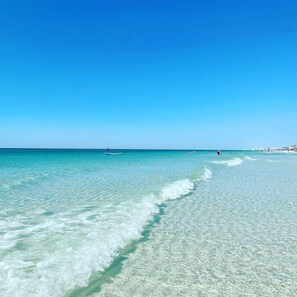 A beach with clear turquoise water, a few people, and a distant shoreline with buildings. - 🏝Stunning Retreat-Private Beach-Umbrella Service for 4 - Dog Friendly (Miramar Beach)