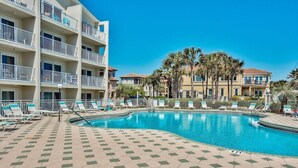 Un hotel con piscina, varios balcones y palmeras.