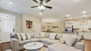 A modern living room with a sectional sofa, a round coffee table, and a ceiling fan. - Minutes from LSU, SU, & Downtown Baton Rouge! (Brusly)