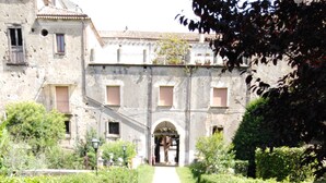 A gravel pathway leading to a stone building with arched entrances.