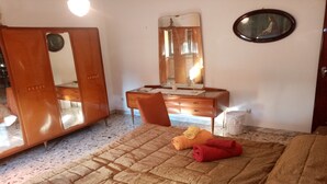 A bedroom with a bed, a wooden dresser, a mirror, and a small table.
