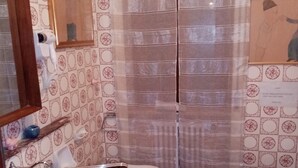 A bathroom with two toilets, a sink, and a shower curtain.