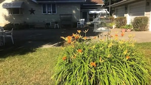 A residential house with a star on the wall, a barbecue grill, and a flower bed in the yard. - The Gathering Place, rent the entire home (Erie)