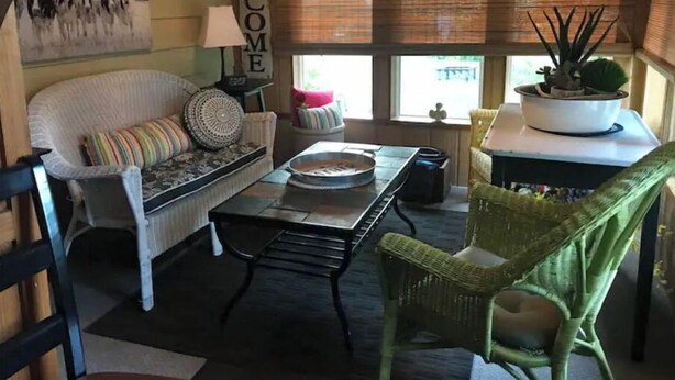 A cozy living room with a white sofa, a green chair, a coffee table, and a 'WELCOME' sign on the wall. - The Gathering Place, rent the entire home (Erie)