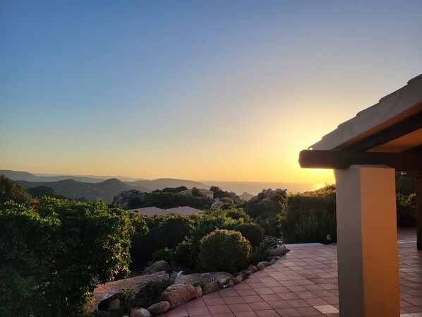 Una terraza con vistas a colinas distantes y un atardecer.