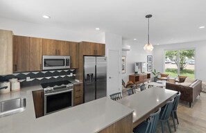 A modern kitchen with a central island, stainless steel appliances, and a dining area with a view. - South Side Modern | DT Chattanooga| A+ Walkable (Chattanooga)