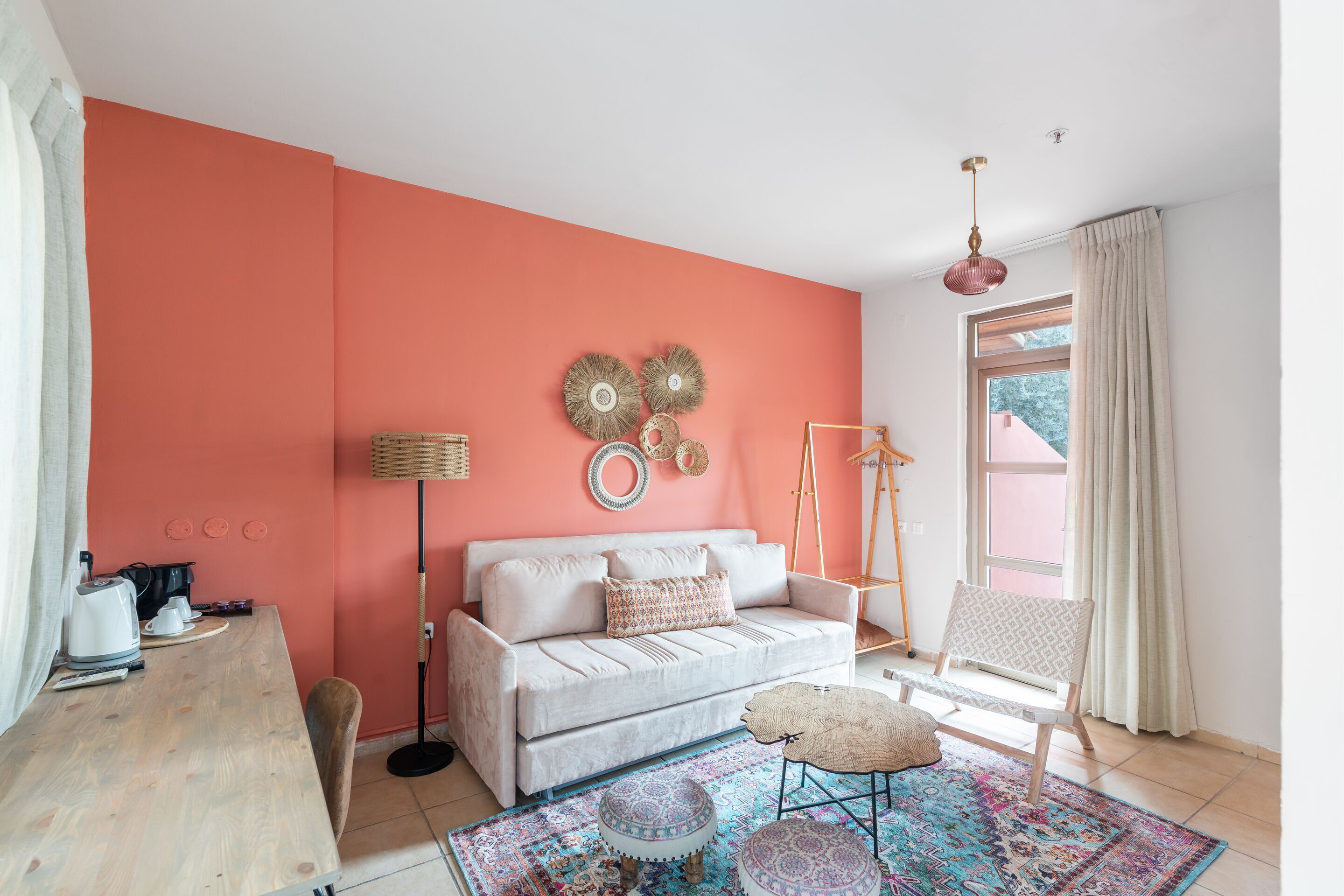 A cozy room with a white sofa, a patterned rug, and a wooden desk with a kettle.