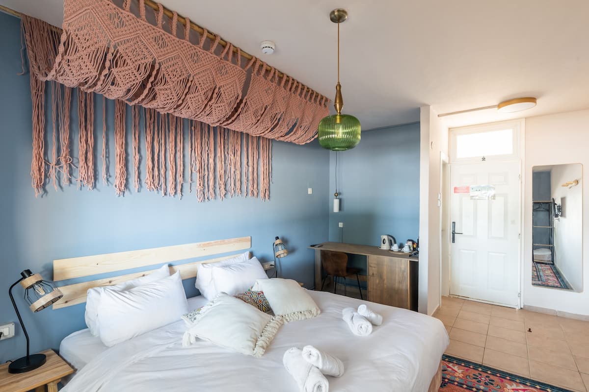 Ein Schlafzimmer mit Bett, Schreibtisch, Stuhl und einer Wanddekoration aus Makramee.