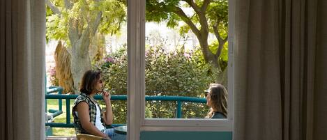 Una habitación con un gran ventanal, vistas a un jardín y una silla.