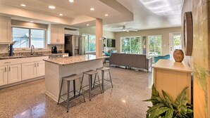 A spacious kitchen with a central island, bar stools, and a ceiling fan. - Pet-Friendly Waterfront Home - 2 Mi to Beach! (Tarpon Springs)