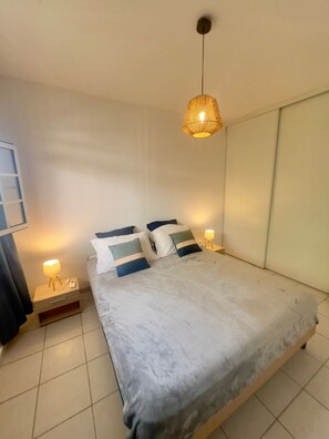 Une chambre moderne avec un grand lit, des tables de chevet avec des lampes et un luminaire suspendu.