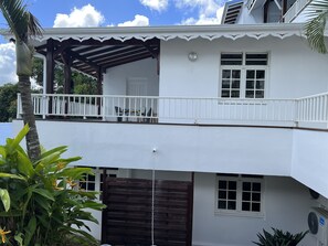 A two-story building with a balcony, white exterior walls, and a covered patio area. - Villa Iguana, peaceful duplex, magnificent view of the sea and Diamond Rock, swimming pool (Sainte-Luce)