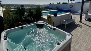 A rooftop pool area with a hot tub, lounge chairs, and a view of the cityscape. - Luxury villa - with a heated pool, hot tub, sea views, aircon, WiFi, UK TV (Playa Blanca)