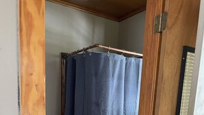 Une salle de bain avec une porte en bois, des toilettes blanches et un rideau de douche bleu.