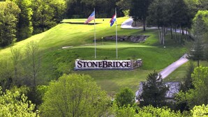 Un terrain de golf avec un panneau indiquant « StoneBridge » et deux drapeaux.