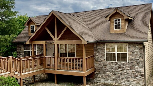 Un chalet avec une façade en pierre, une terrasse en bois et un petit balcon.