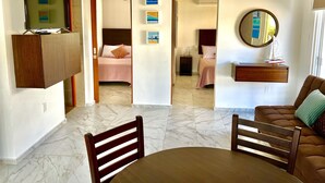 A hotel room with a bed, bedside table, and a TV mounted on a wooden cabinet. - Beautiful apartment with balcony, pool, Roof Top in Punta Sur at Casa Ama 2 (Isla Mujeres)