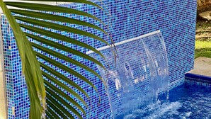A swimming pool with a blue mosaic tile wall and a waterfall feature. - Gorgeous cozy apartment with pool, balcony and roof top in Punta Sur! Casa Ama 4 (Isla Mujeres)